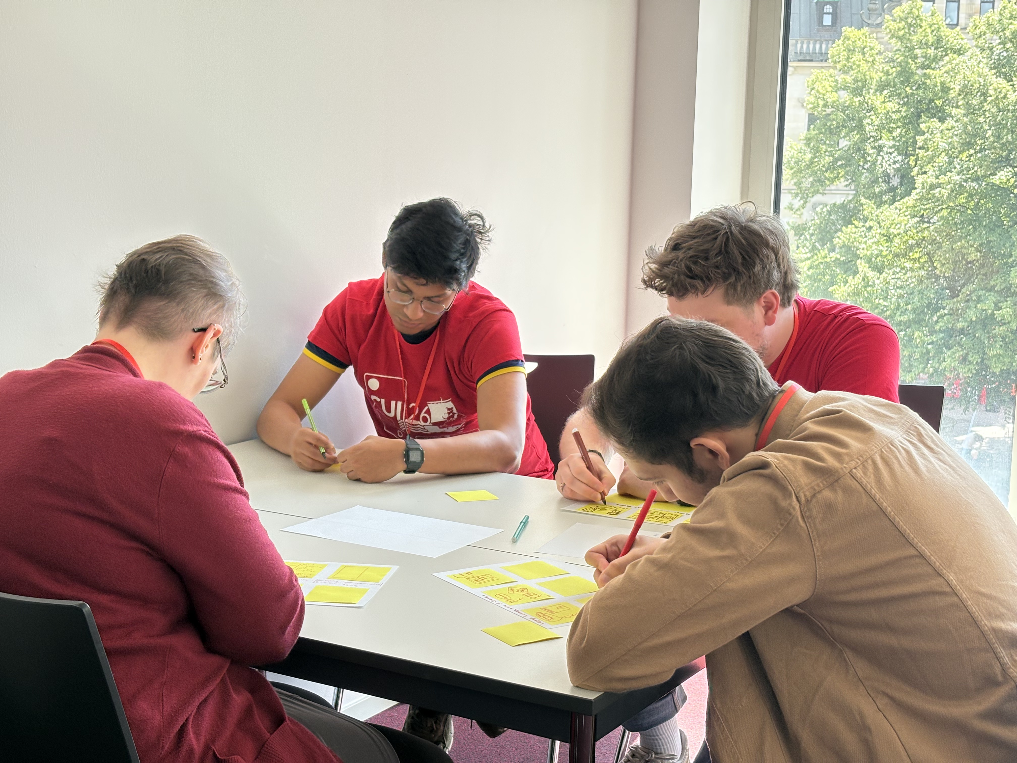 Group 3 showing the four members writing their storyboards while sitting in circle around a table